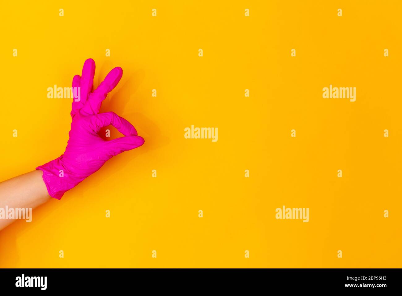 Hand in pink protective rubber glove showing nice sign isolated on ...