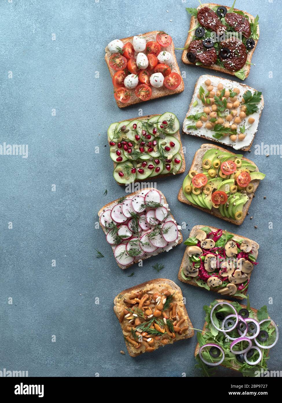 Assortment vegan sandwiches on gray stone background. Set different vegetarian smorrebrod. Top view or flat lay. Vertical Stock Photo