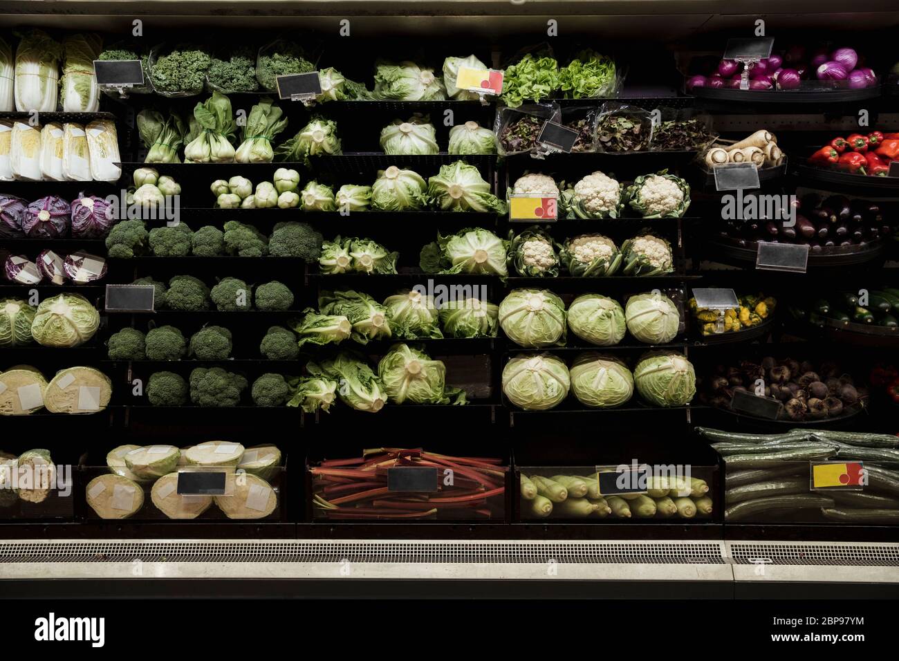 A wide-view shot of an abundance of fresh vegetables on display at a market stall. Stock Photo