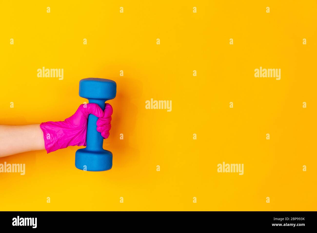 Hand in pink protective rubber glove with dumbbell isolated on yellow ...