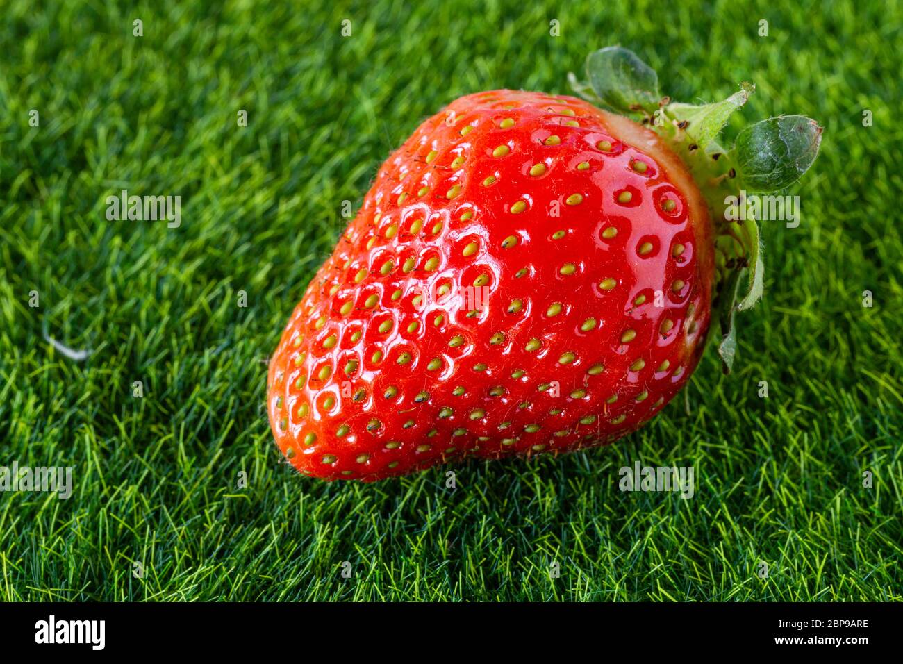 Strawberries on a green background. Red, seasonal fruit. Strawberries on the grass. Fruit for dessert. Juicy and sweet. Strawberries from the garden. Stock Photo