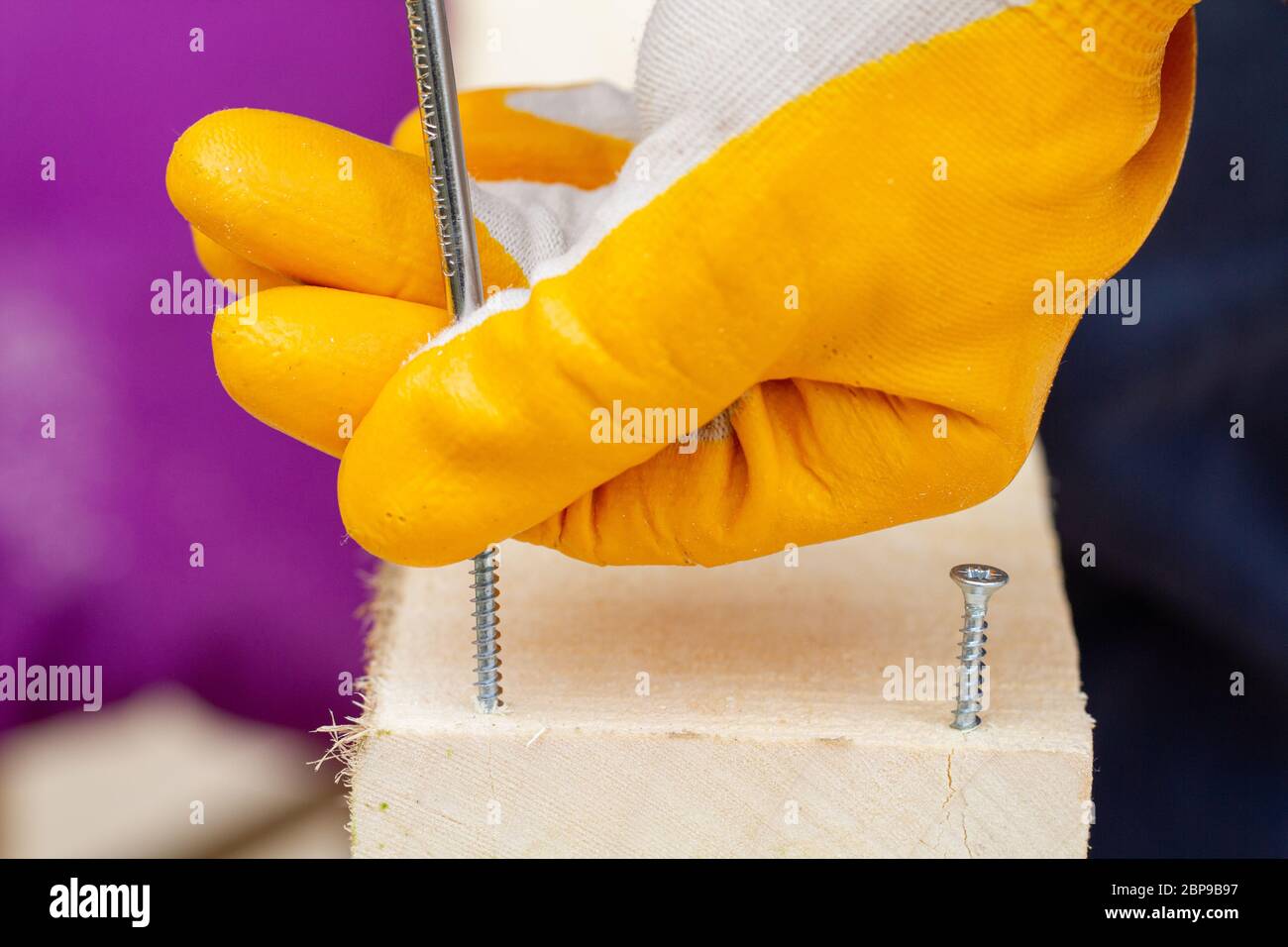 Crop view driving selftapping screw into chipboard placed on wooden