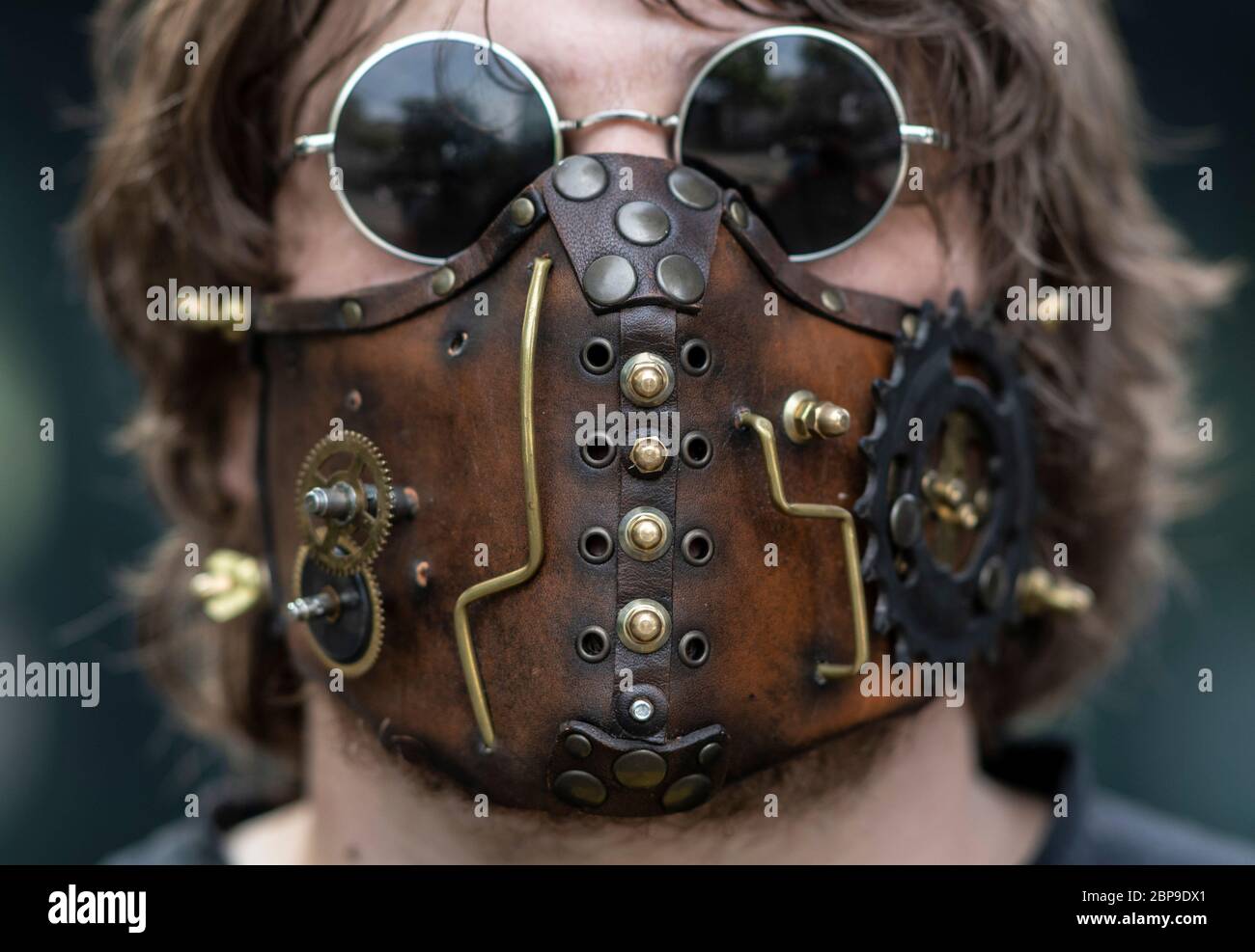 Frankfurt, Germany. 18th May, 2020. 18 May 2020, Hessen, Frankfurt/Main: With a 'steampunk' mask this young man protects himself from the corona virus before entering a shop. Among other things, 'steampunk' is used to describe inventions and designs that never existed in the real world, but which are based on the beginning of industrialization in the mid-19th century. Photo: Boris Roessler/dpa Credit: dpa picture alliance/Alamy Live News Stock Photo