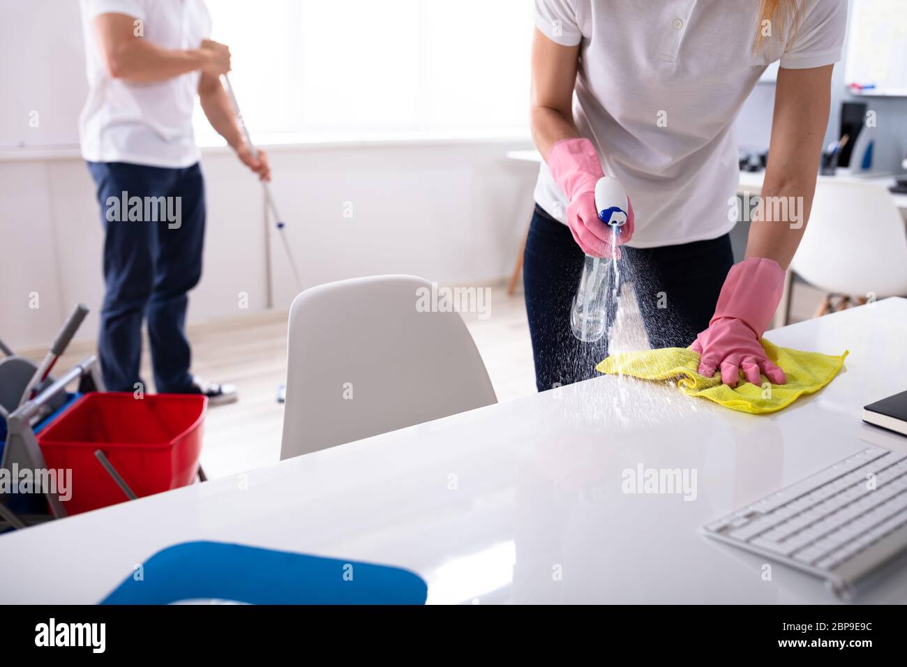 Two Janitor Cleaning The Desk And Mopping Floor In The Office Stock Photo