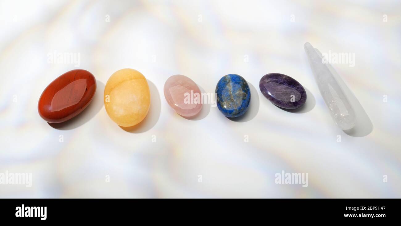 Semi precious stones in a row. Garnet, Carnelian, Rose Quartz, Lapis Lazuli, Amethyst and quartz. Chakras. Stock Photo