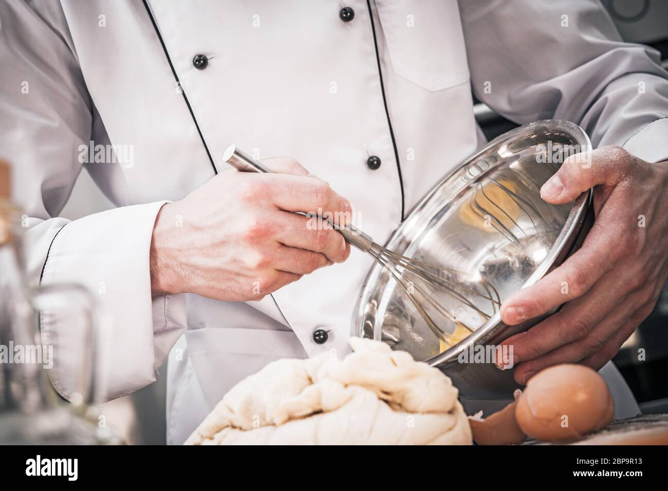 Caucasian Male Chef Mixing Batter With Wire Whisk In Stainless Steel Bowl. Stock Photo