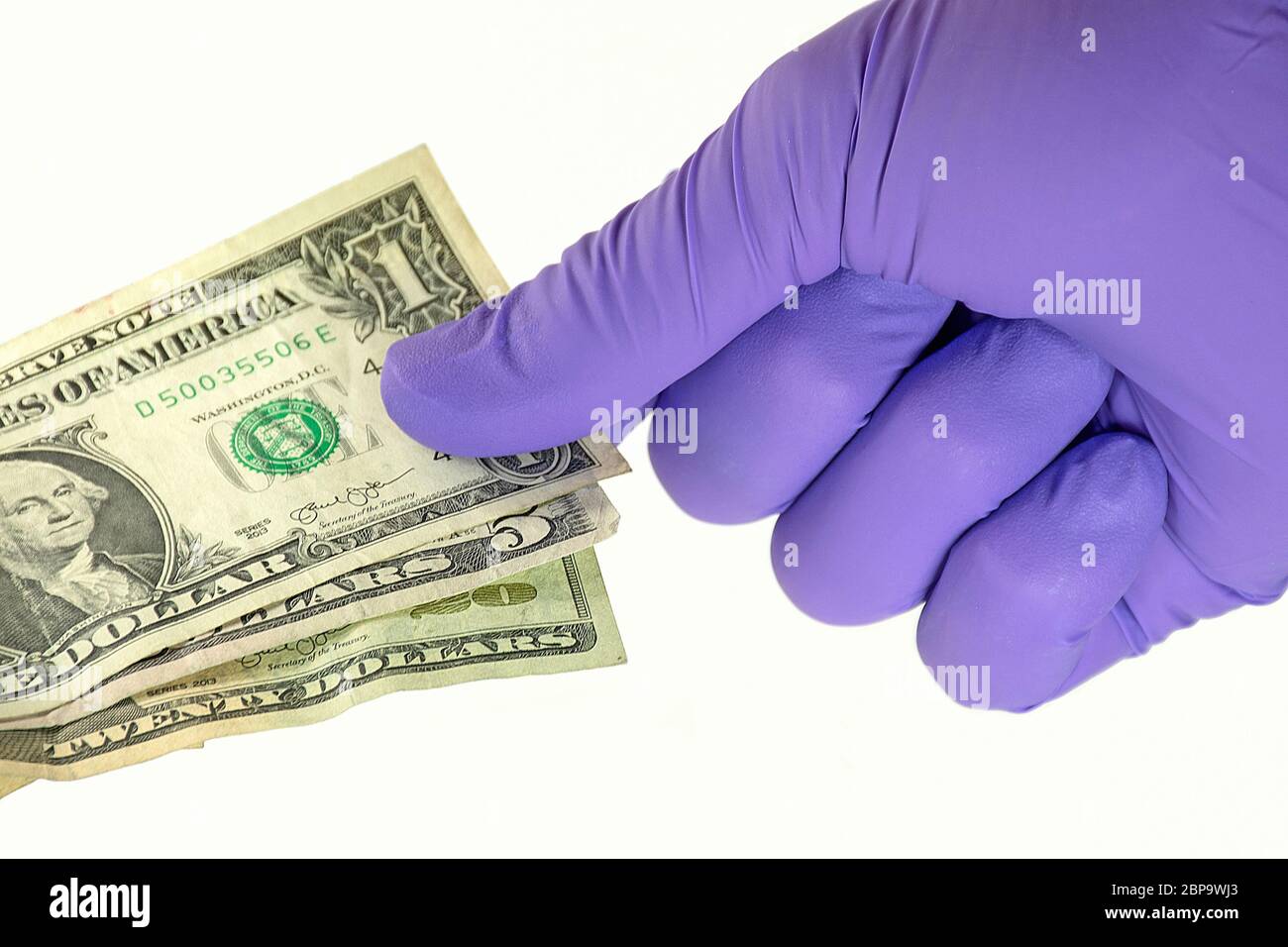 purple latex glove protecting hand from germs on dollar bills Stock Photo
