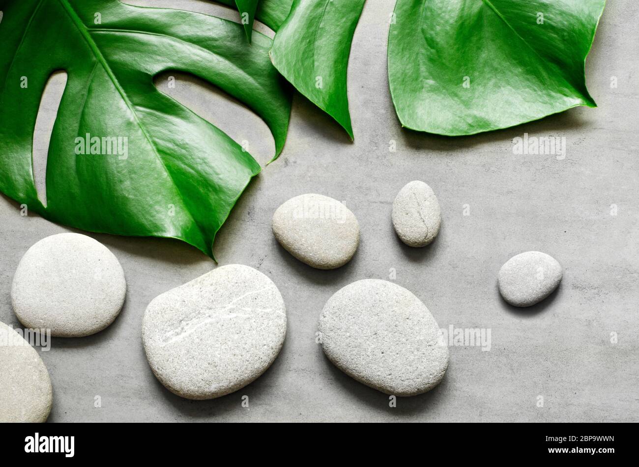 Flat lay composition with spa stones, palm leaves on grey background ...