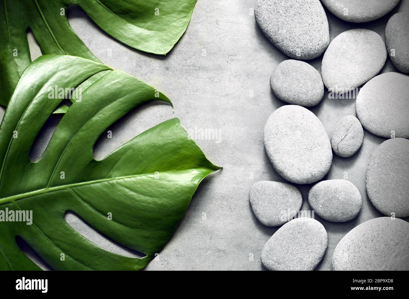 Flat lay composition with spa stones, palm leaves on grey background ...