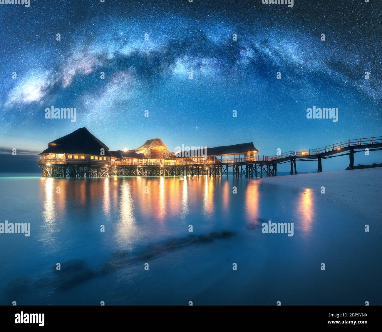 Milky Way and wooden bungalow on the water in summer starry night Stock Photo