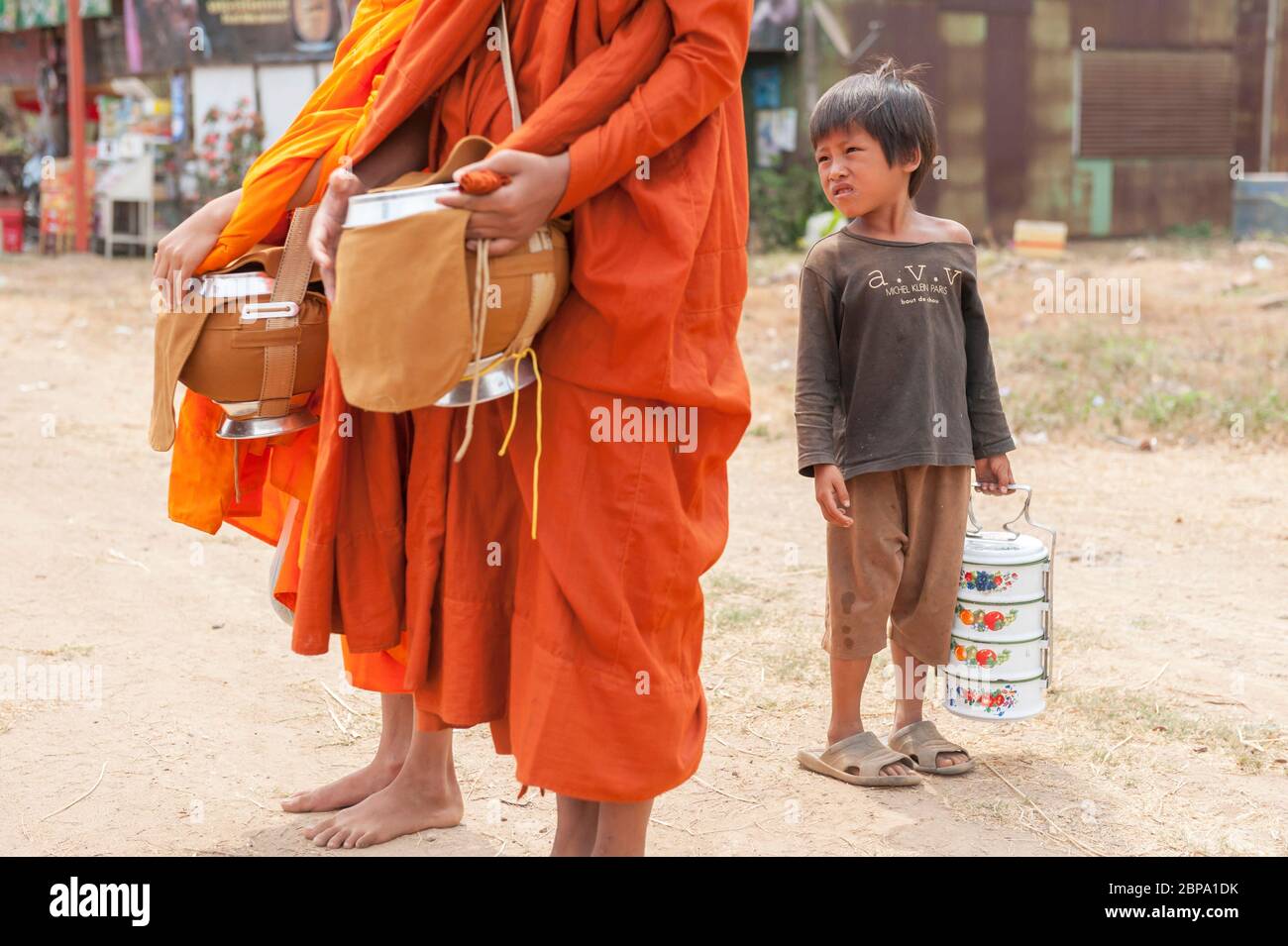 A young Cambodian boy looks on as buddist monks stop for almsgiving. Central Cambodia, Southeast Asia Stock Photo