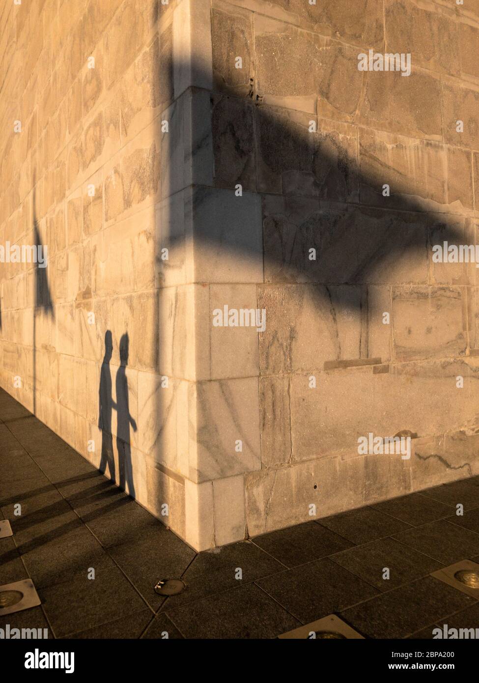 Shadow of visitors and waving flags cast upon the base of the Washington Monument at sunset, Washington, D.C., USA Stock Photo