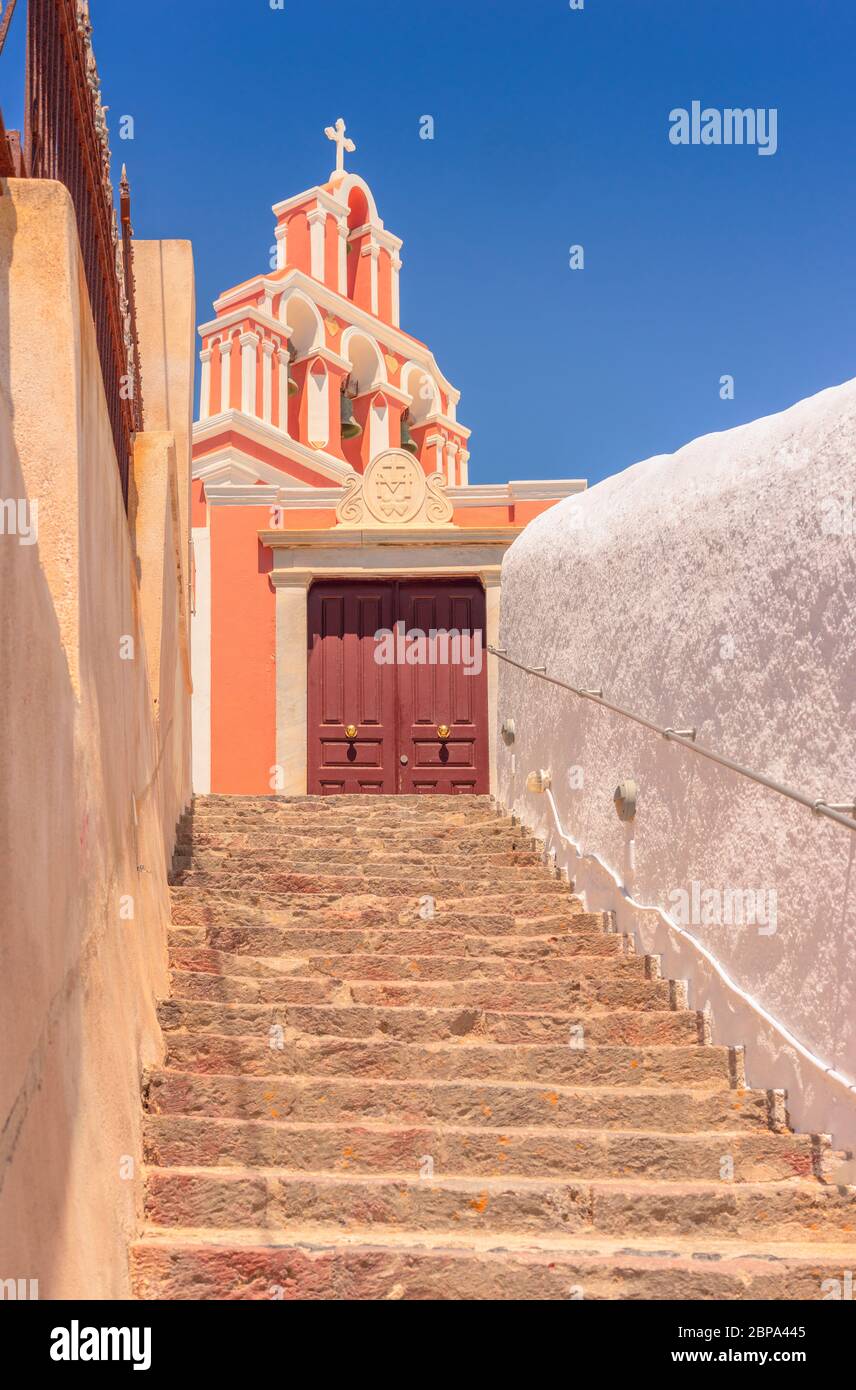Looking up the stone steps that lead to church yard doors and the colourful bell tower above, in Fira, on the greek island of Santorini Stock Photo