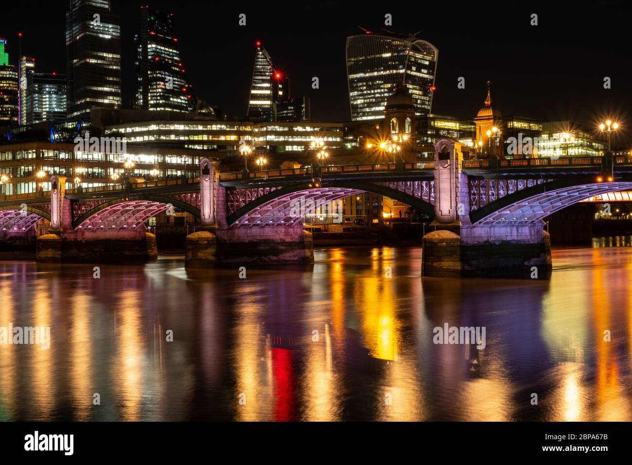 Southwark Bridge at night from the south bank with City of London in the backgound. Illuminated River project Stock Photo