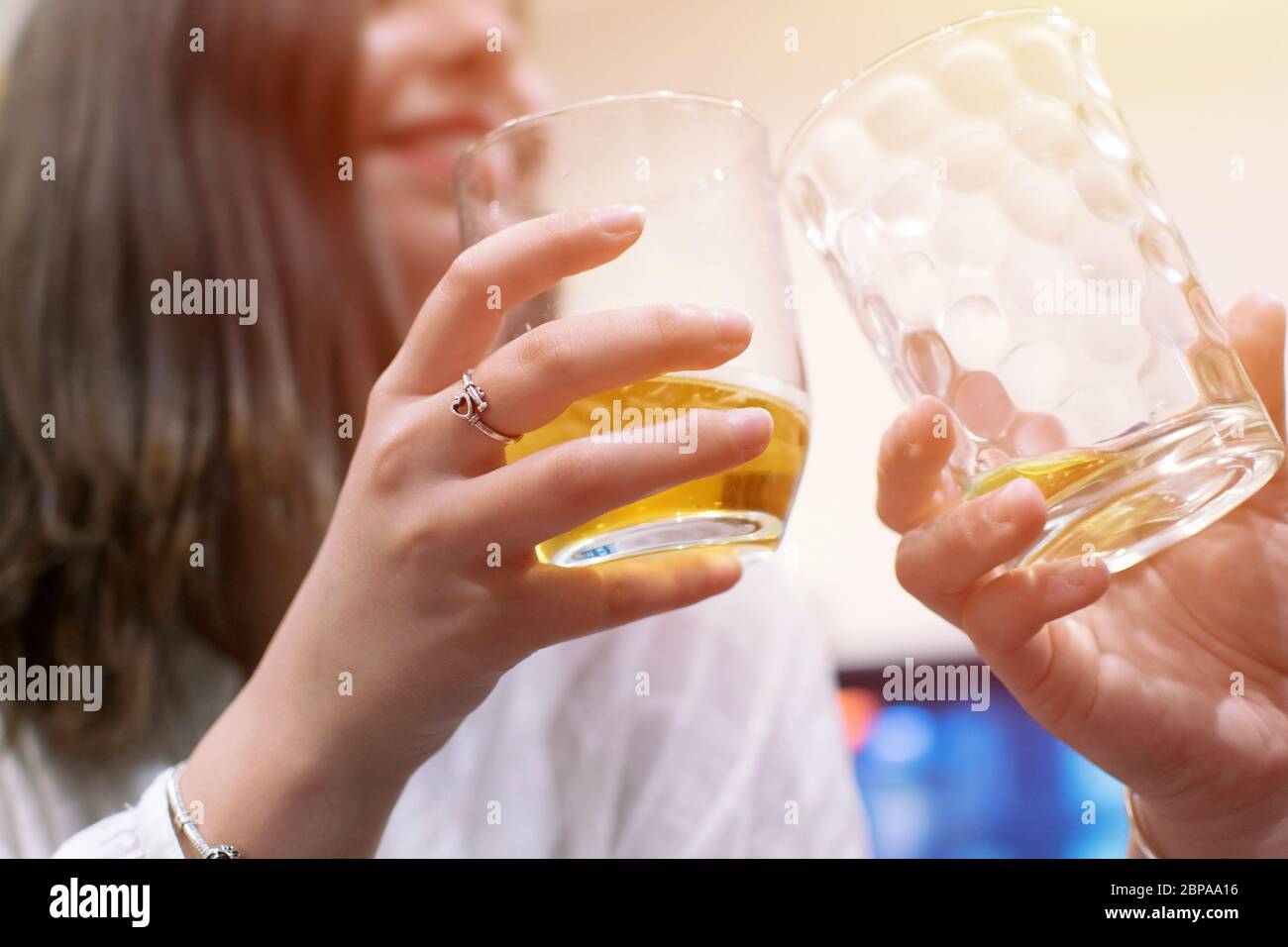 Drink craft beer with a friend, clink glasses. Two hands holding two glasses of beers Friendship concept. Young cute girl friends holding glasses toge Stock Photo