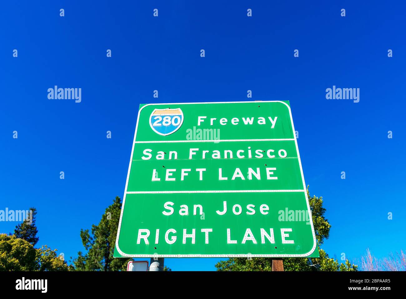 Interstate 280 highway road sign providing information to drivers the directions to San Francisco and San Jose in sunny Silicon Valley. Green trees an Stock Photo