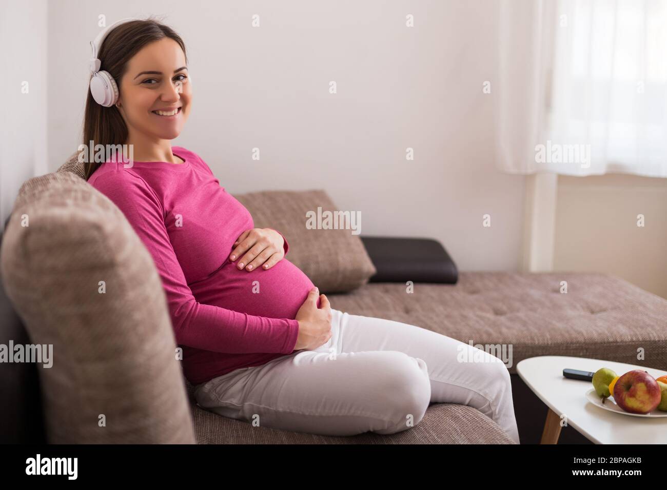 Beautiful pregnant woman enjoys listening music at her home Stock Photo ...