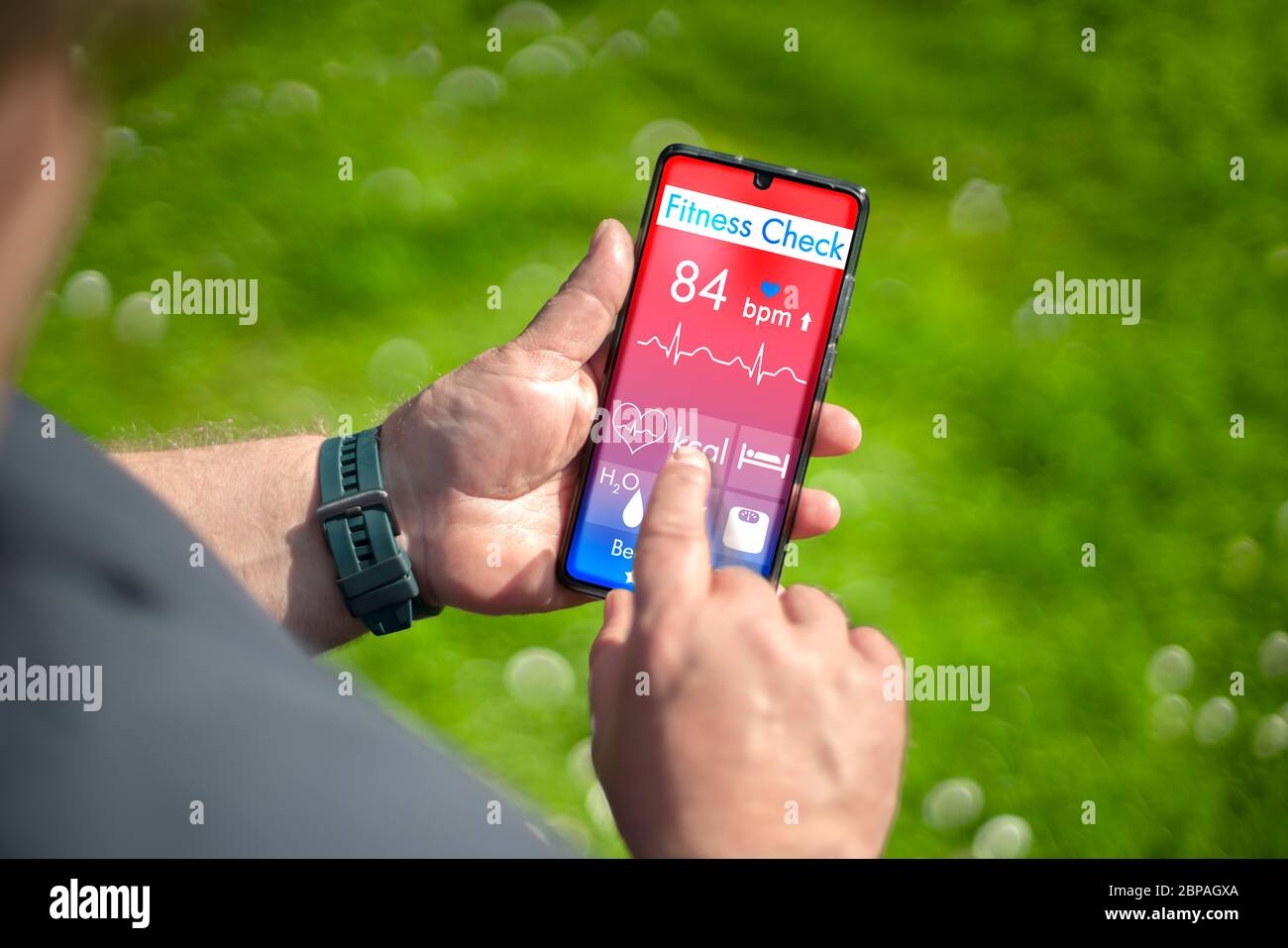 The hand of a chubby man holds a smartphone in his hand. A fitness app is installed on the mobile phone. The app is fictitious and self made. Stock Photo