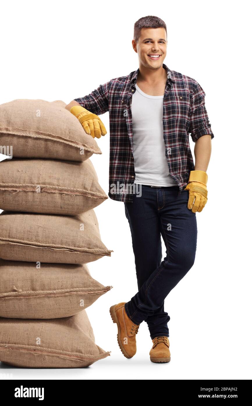 Full length portrait of a farmer leaning on a pile of sacs isolated on white background Stock Photo