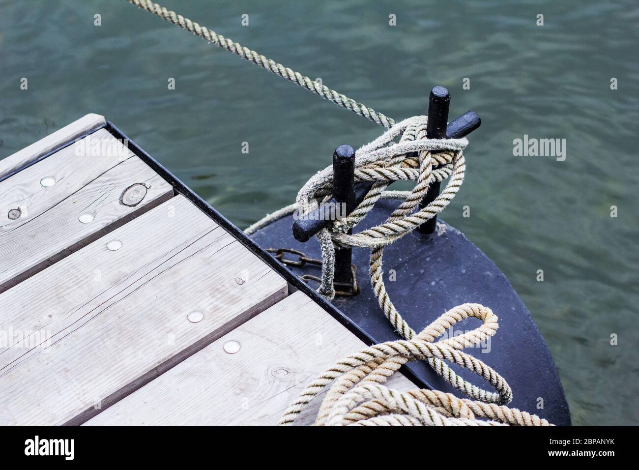 Ship line moored to the mooring post on a modern wooden jetty hobby safety pile group risk of tripping pier expert knowledge Stock Photo