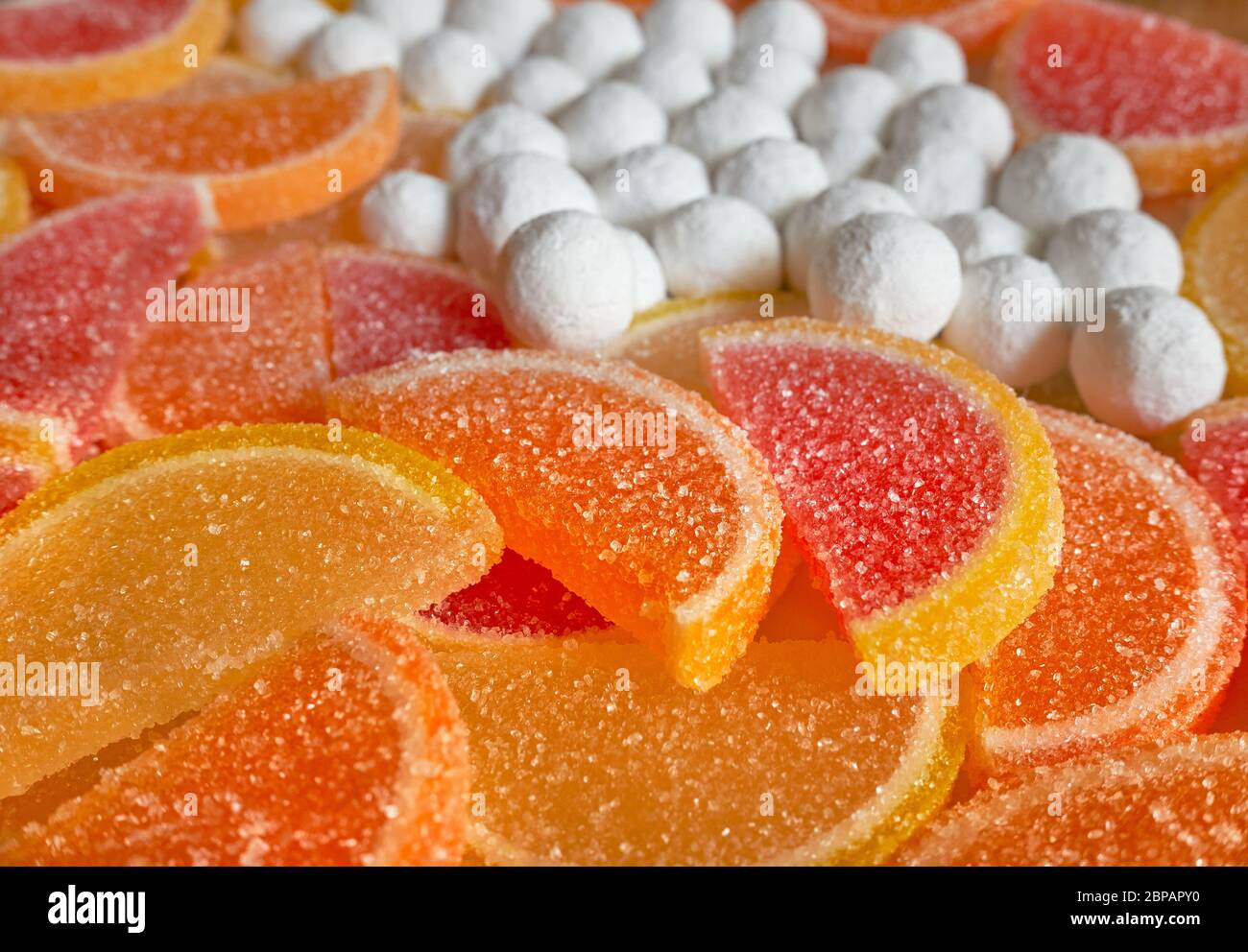 Fruit jelly slices in sugar and cranberries in powdered sugar, close
