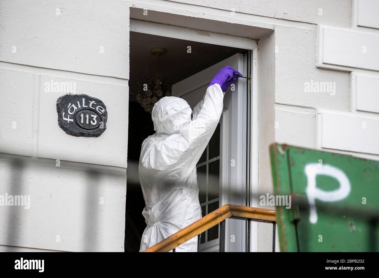 A forensic officer works at a property in Lenadoon Avenue in west Belfast, following the murder of 57 year old Keiran Wylie who was murdered at his home on Sunday night. Stock Photo