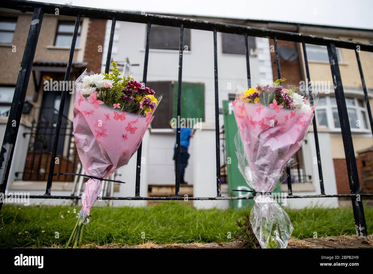 Flowers are left at the scene as shutters are placed against the windows of a property in Lenadoon Avenue in west Belfast, following the murder of 57 year old Keiran Wylie who was murdered at his home on Sunday night. Stock Photo