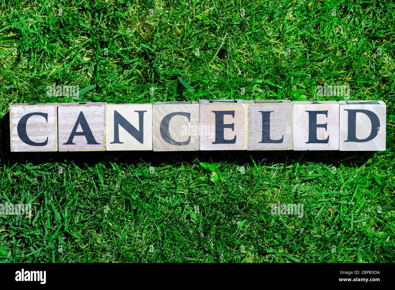 Canceled written on wooden blocks isolated on a green gras background Stock Photo