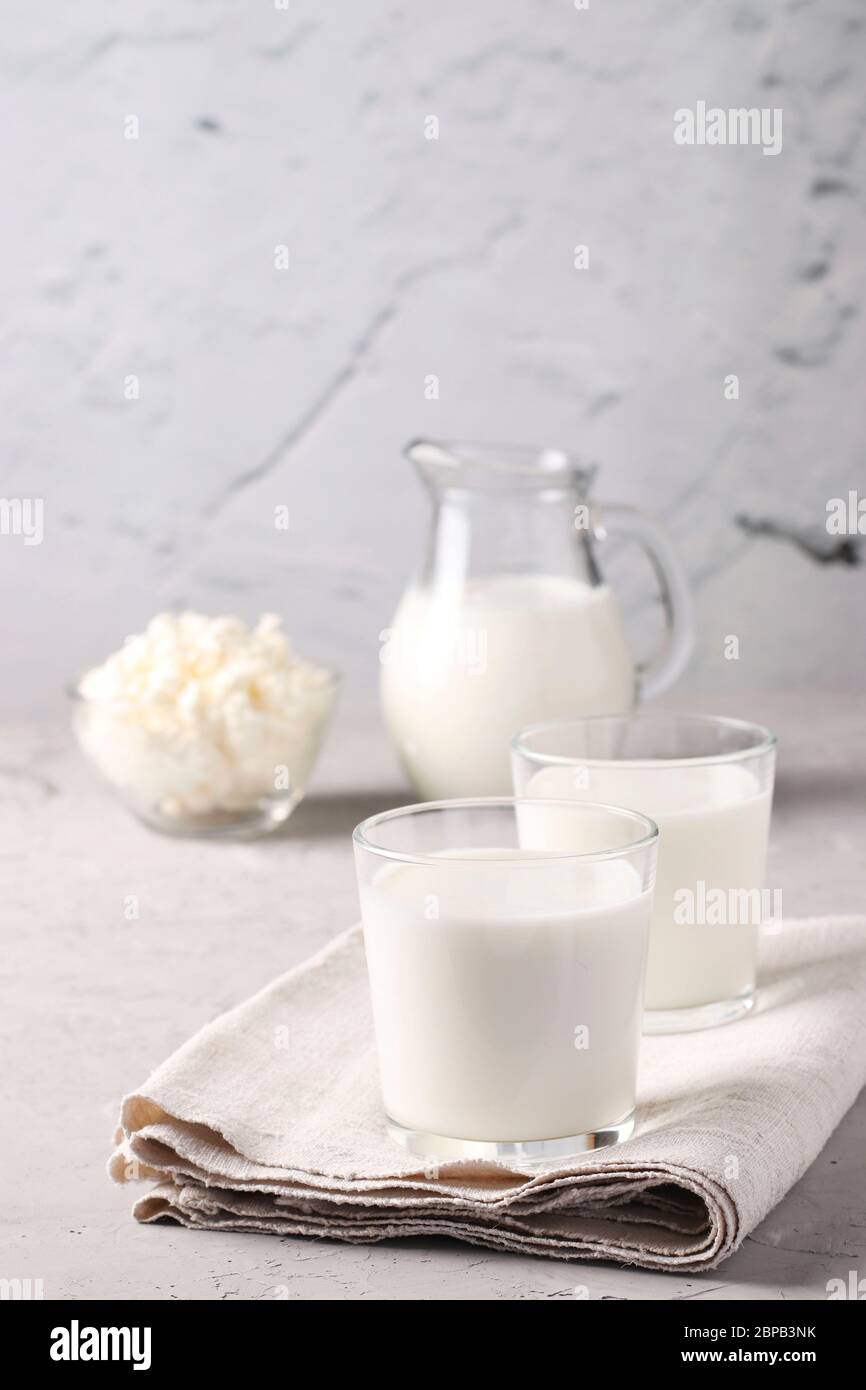 Kefir or Ayran fermented drink in two glasses, milk in jug and cottage cheese in a bowl on light gray background, Vertical format Stock Photo