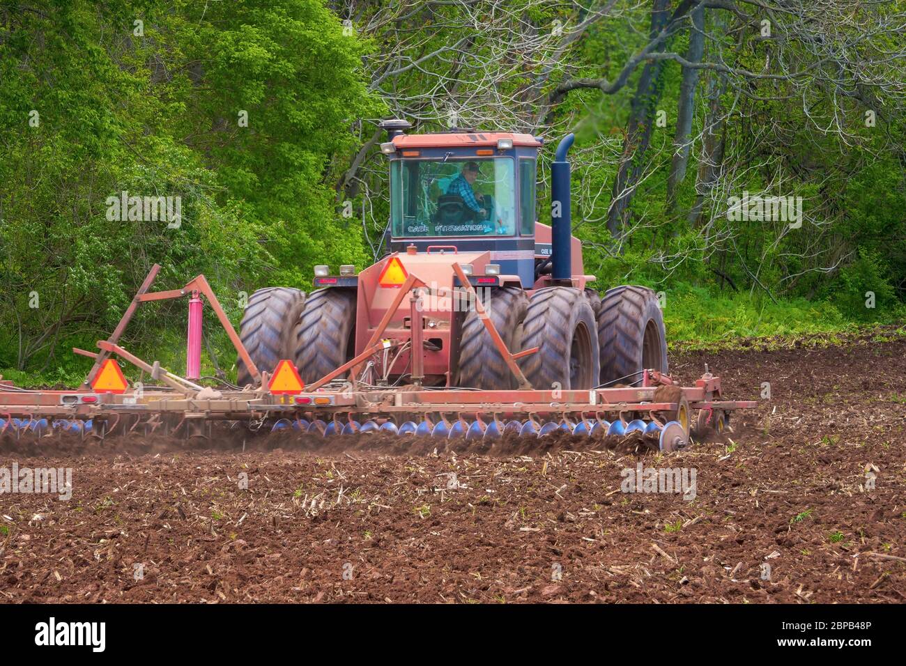 A farmer uses a tractor to disc a field for corn planting May 12, 2020 in Frederick County, Maryland. Stock Photo