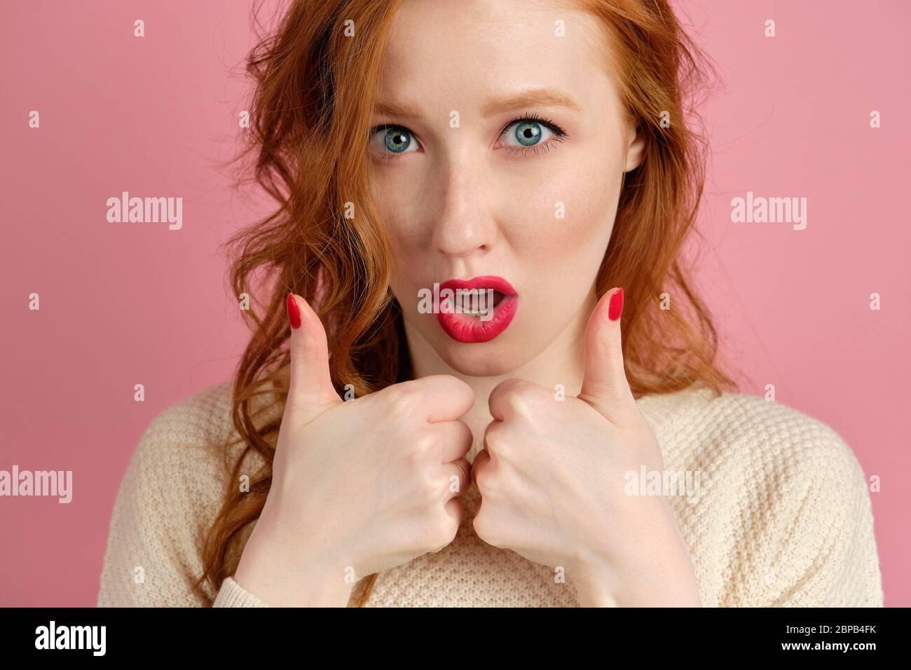 A Red Haired Girl With Blue Eyes And Red Lips Looks Into The Frame And Shows Her Thumbs Up Stock Photo Alamy