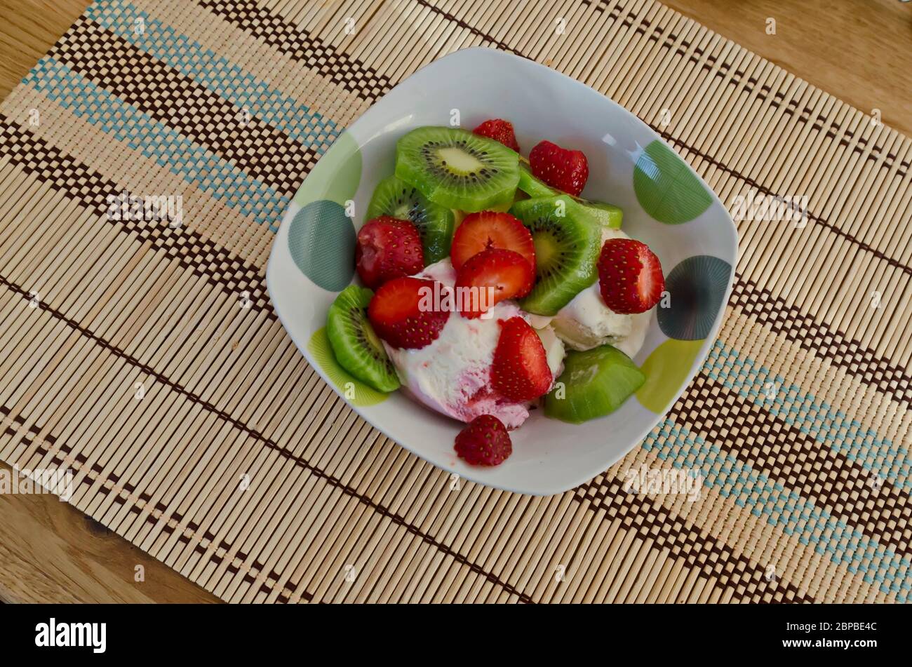 Appetizing dessert of freshly ripe sliced strawberries and kiwi-fruit on ice cream, Sofia, Bulgaria Stock Photo