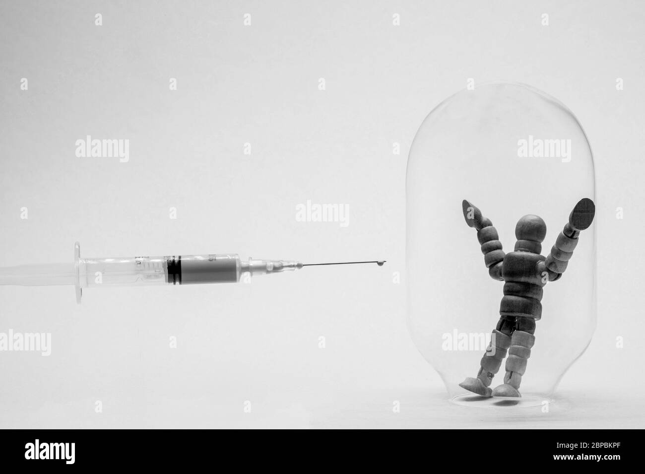 Black and white image. A man in a glass flask symbolizing immunity is trying to protect himself from vaccination against coronavirus. Stock Photo