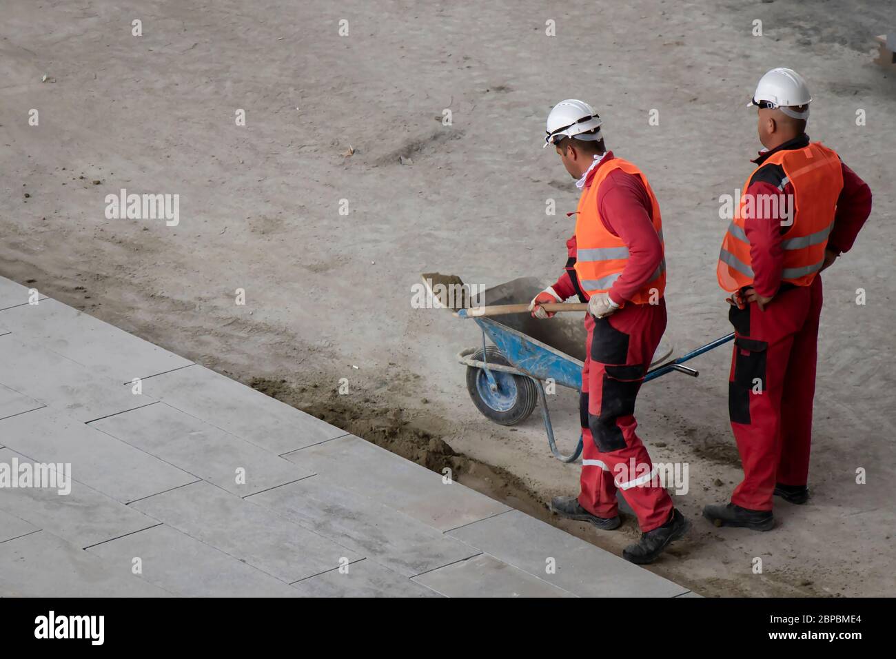 Belgrade, Serbia - May 18, 2020: Construction workers working with shovel and wheelbarrow, high angle view Stock Photo