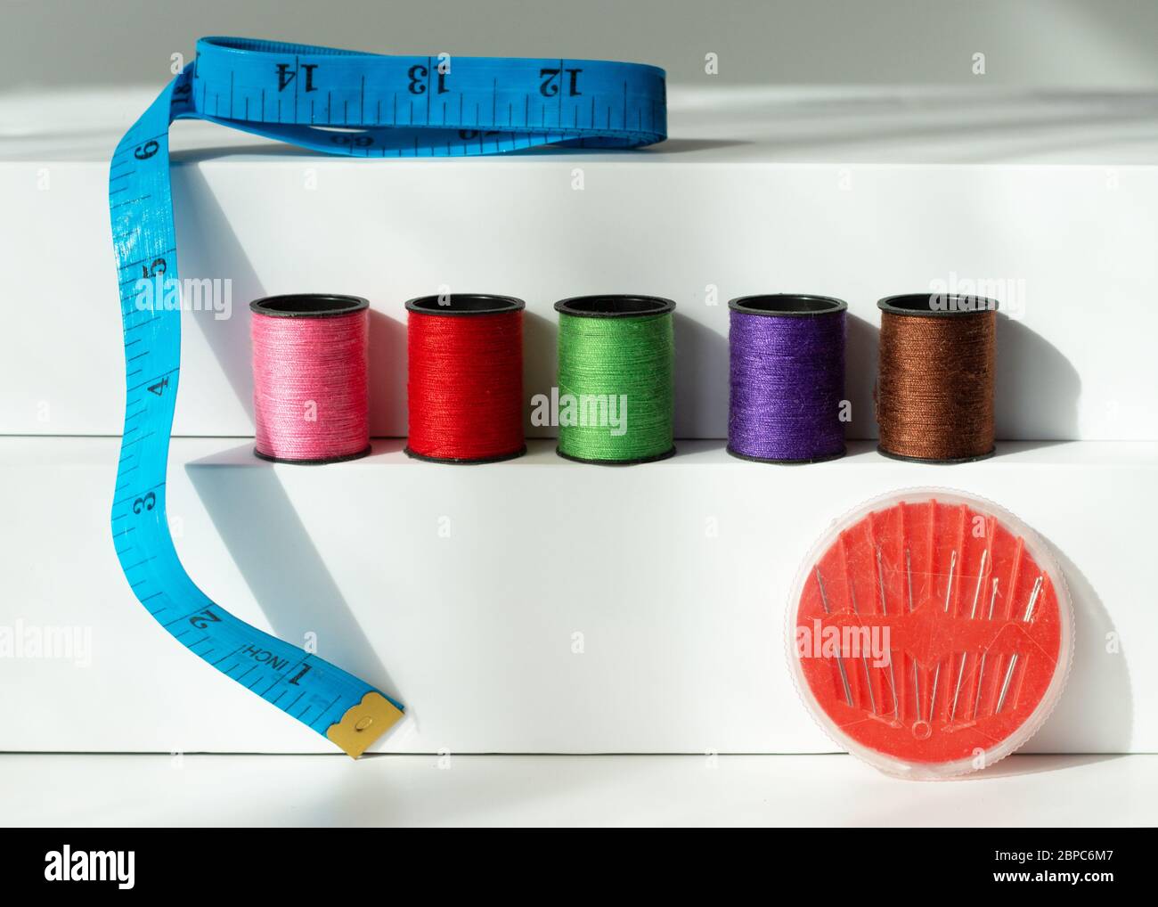 Creative composition with spools of colored threads and scissors. Sewing accessories, tailoring set. Stock Photo