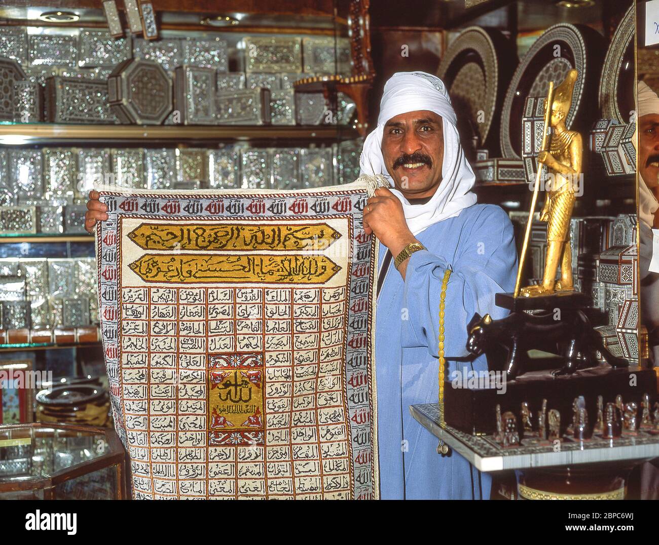 Souvenir shop owner holding carpet, Luxor, Luxor Governorate, Republic of Egypt Stock Photo
