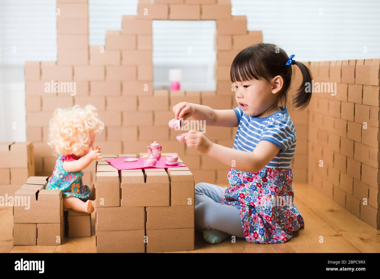 toddler girl pretend play baby care in a carton house Stock Photo Alamy