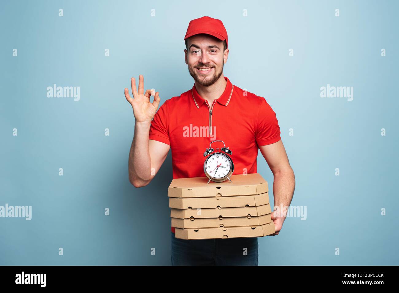 Courier is punctual to deliver quickly pizzas. Cyan background. Stock Photo