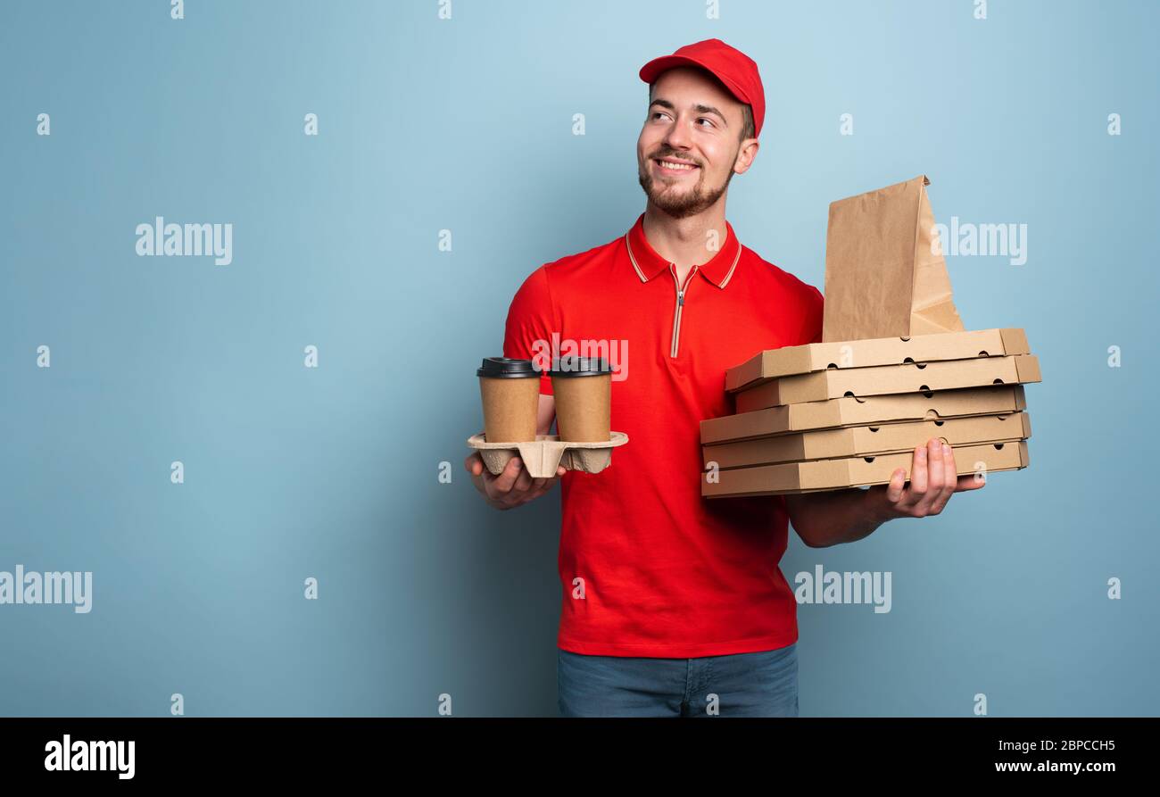 Courier is happy to deliver hot coffee and pizza. Cyan background Stock Photo
