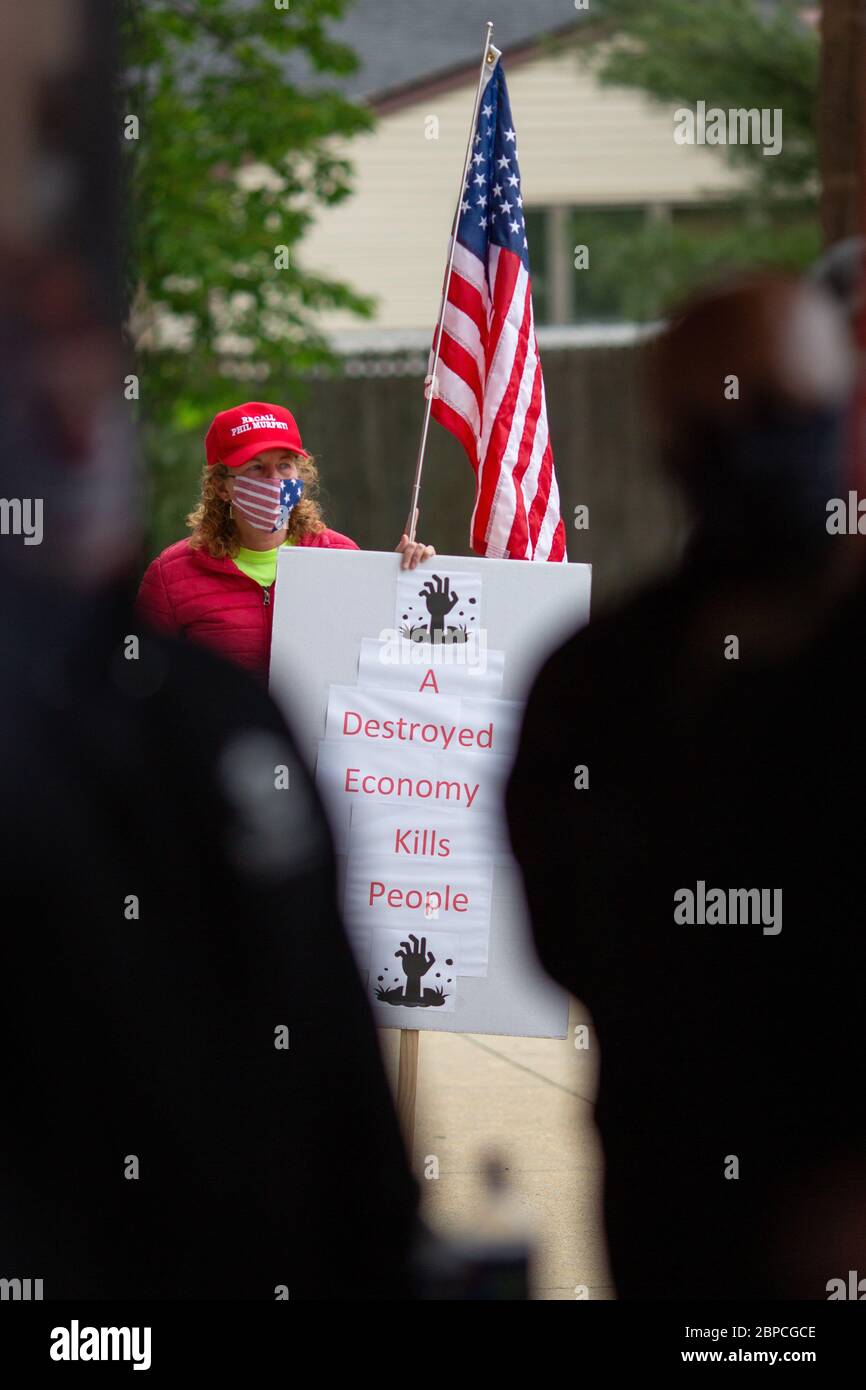 Bellmawr, New Jersey, USA. 18th May, 2020. A woman holds a sign and a flag in front of the Atilis Gym in Bellmawr, NJ, on Monday, May 18, 2020. Credit: Dave Hernandez/ZUMA Wire/Alamy Live News Stock Photo