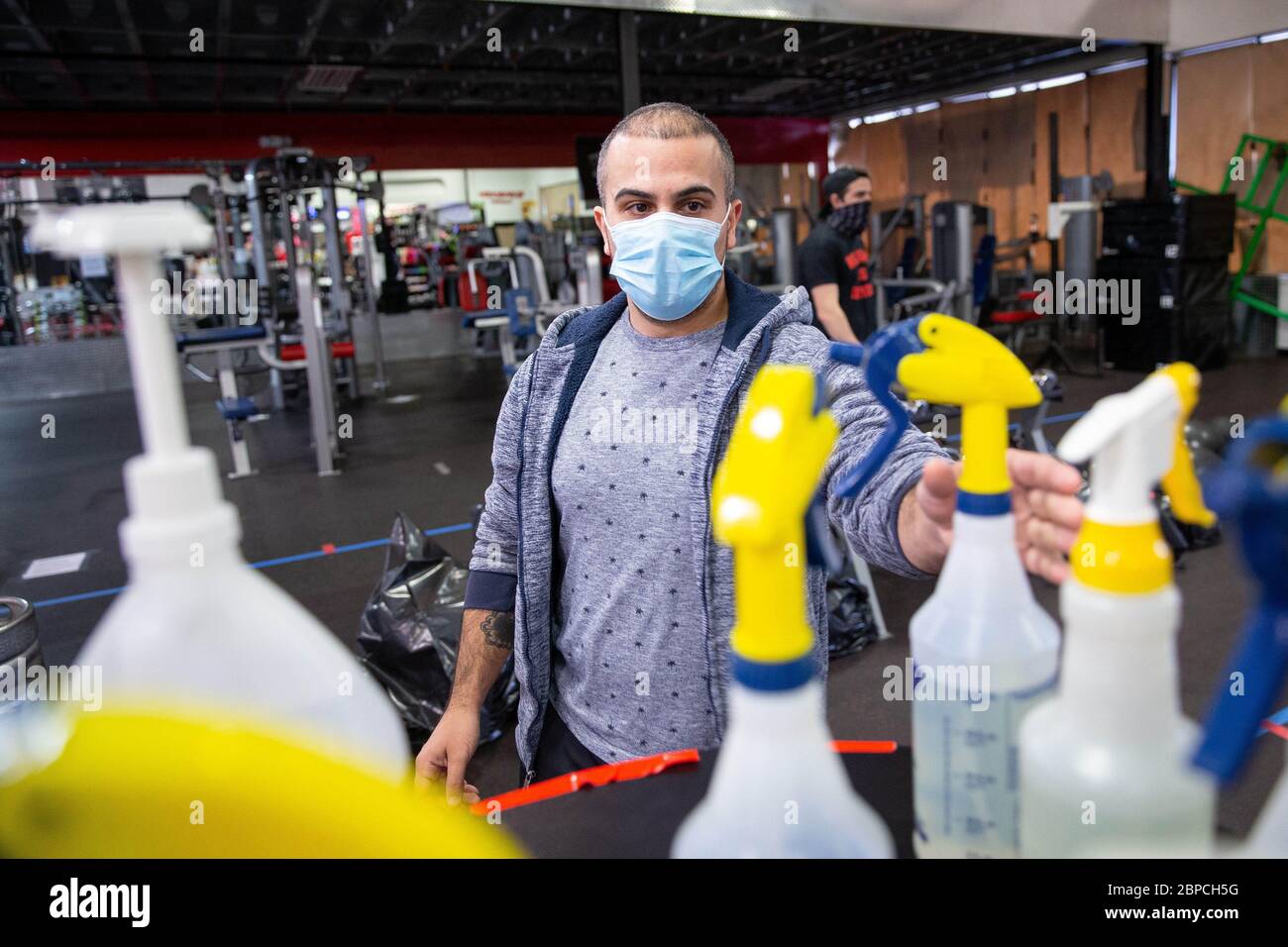 Bellmawr, New Jersey, USA. 18th May, 2020. A member of the gym picks up a bottle of disinfectant upon entry into the Atilis Gym in Bellmawr, NJ, on Monday, May 18, 2020. Every member is issued a bottle of disinfectant to clean equipment both before and after use as required by Atilis Gym in their new rules. Credit: Dave Hernandez/ZUMA Wire/Alamy Live News Stock Photo