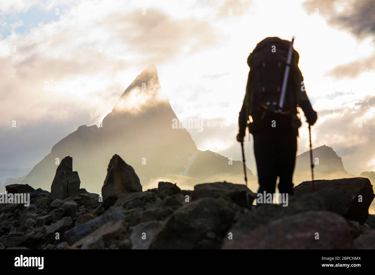 Backpacker approaches dramatic mountain summit, Canada. Stock Photo