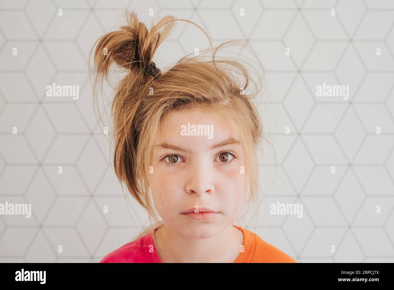 Young girl with hair in a messy bun looking at camera Stock Photo