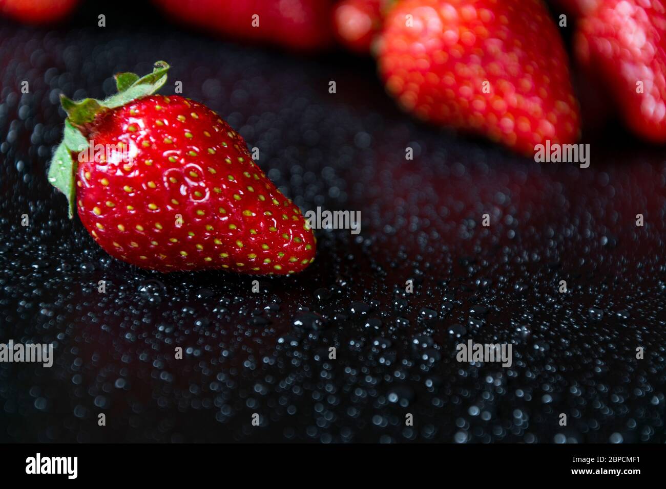 Fresh and juicy red strawberries on black background with drops of ...
