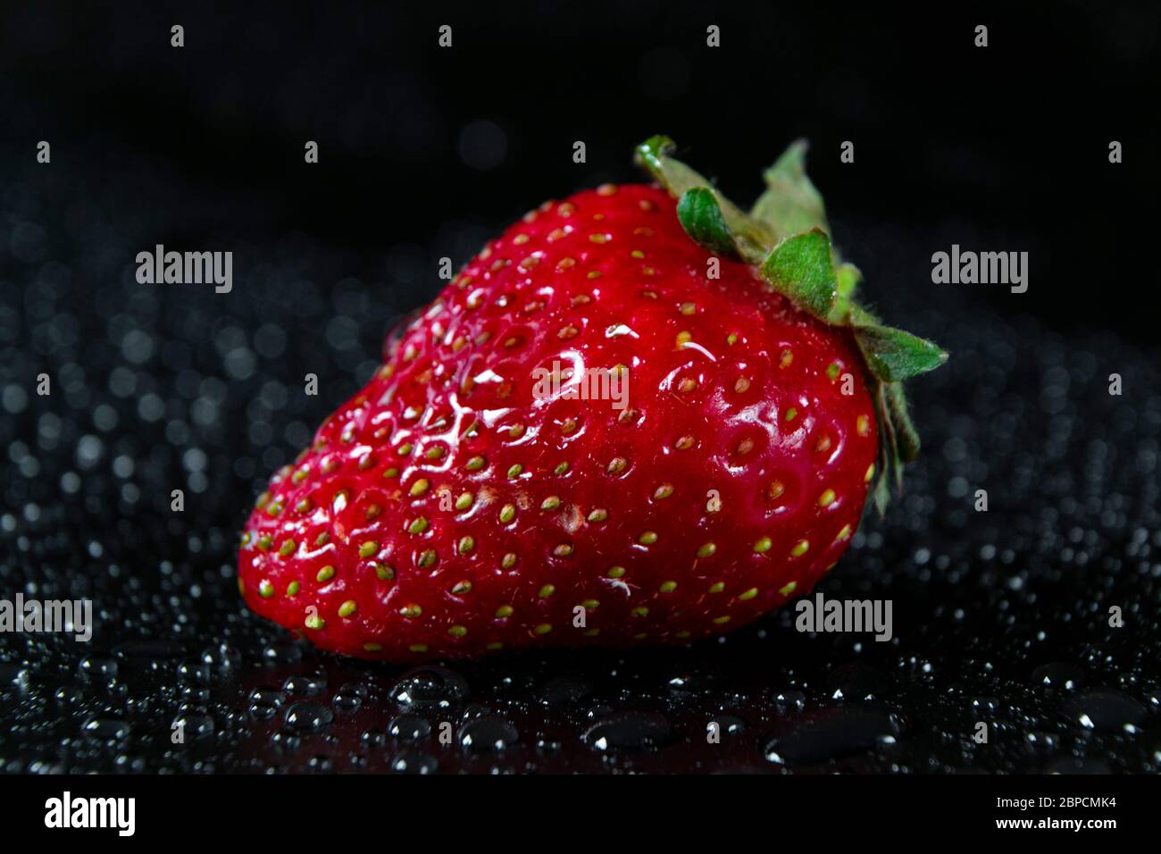 Fresh and juicy red strawberry on black background with drops of water ...