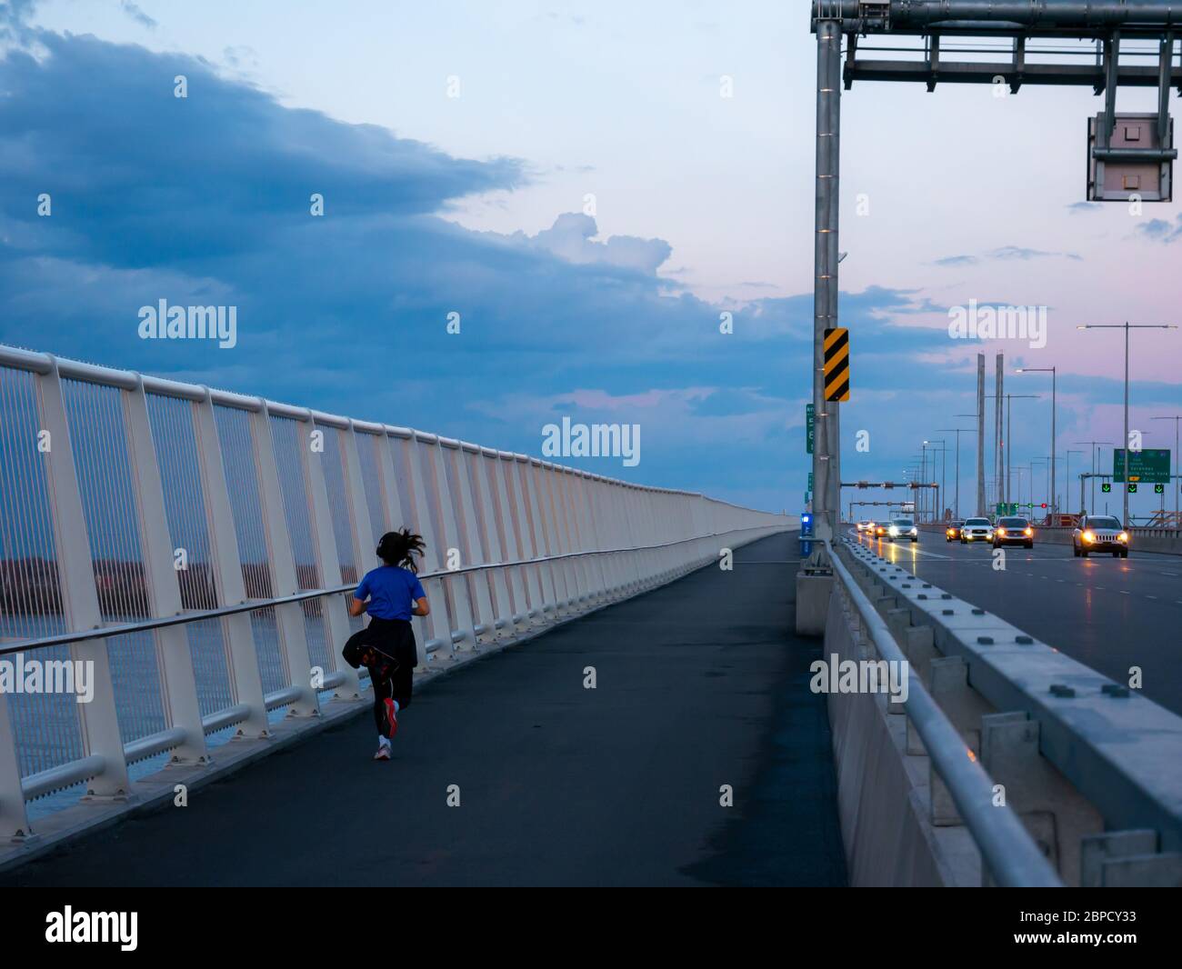 A young woman jogs on the pedestrian lane on Montreal's new Champlai Bridge Stock Photo