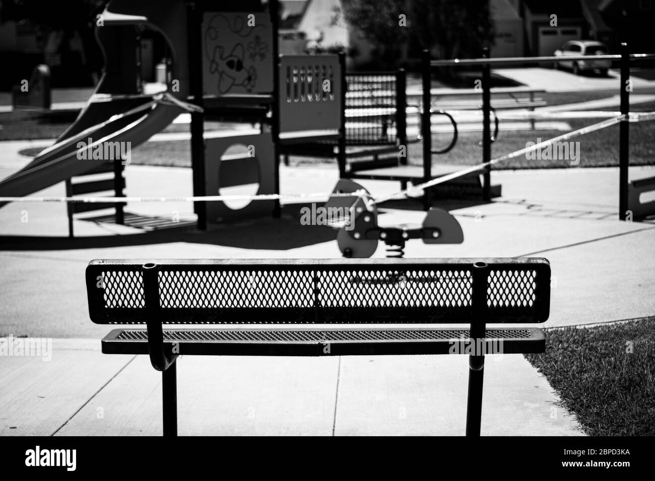 empty park bench in front of playground equipment Stock Photo