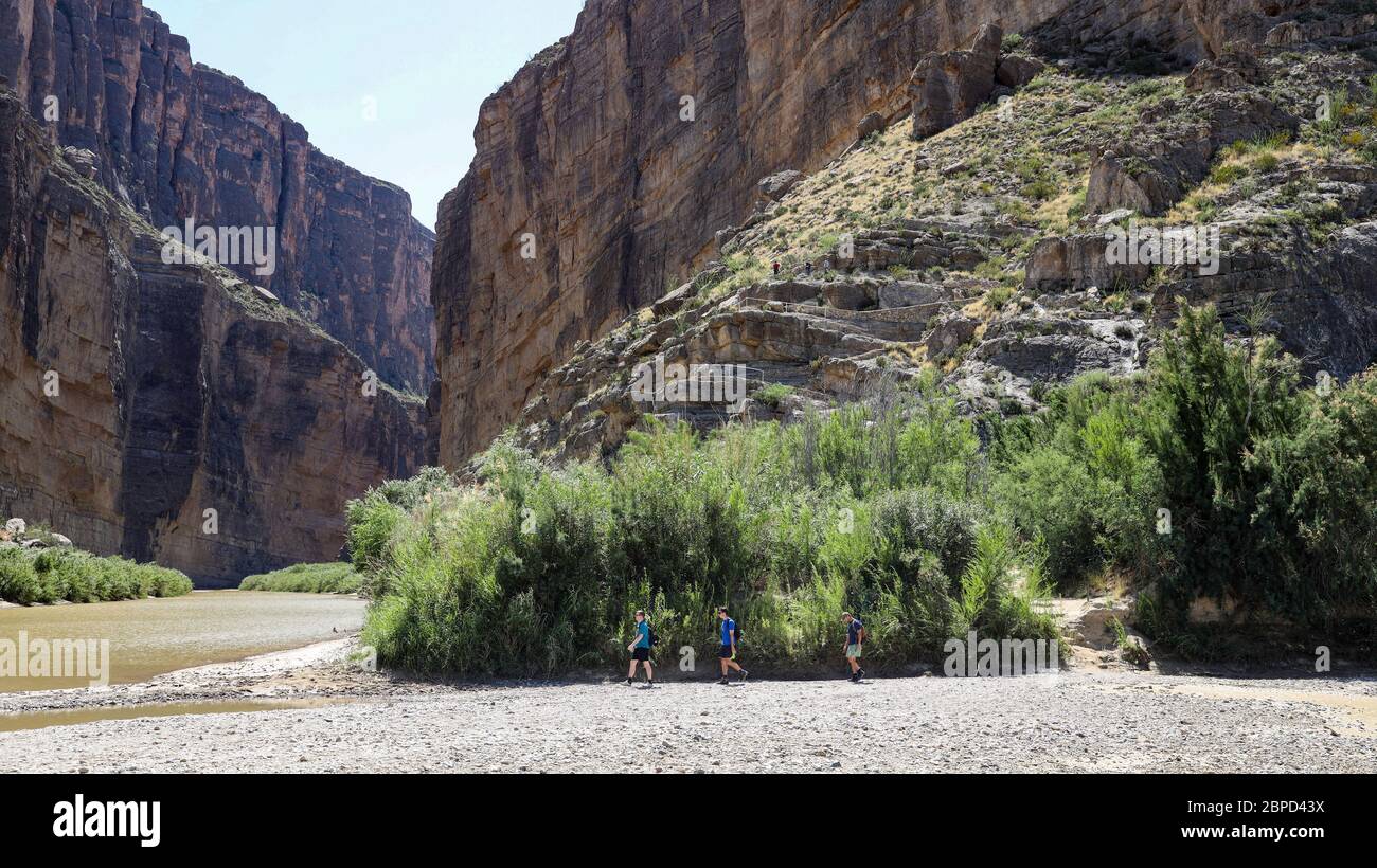Hikers cross dry Terlingua Creek bed at confluence with Rio Grande here at east end of Santa Elena Canyon. Stock Photo