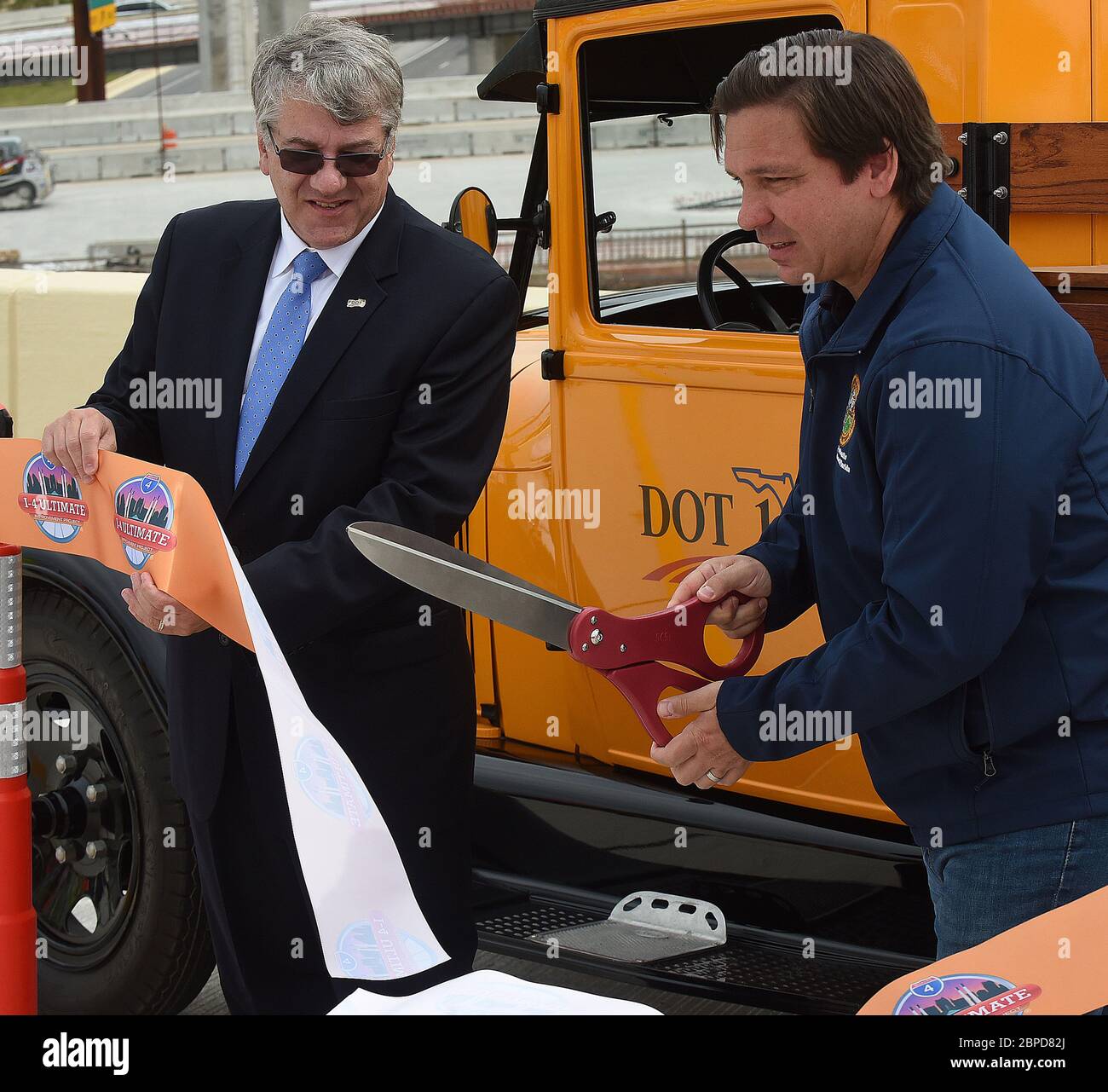 May 18, 2020 - Orlando, Florida, United States - Florida Department of Transportation Secretary Kevin Thibault (left) looks on as Gov. Ron DeSantis cuts the ribbon on the newly completed I-4 and State Road 408 interchange which will open to traffic tonight in downtown Orlando, Florida. DeSantis explained at a news conference that progress on the 21-mile I-4 Ultimate Project was expedited at his direction due to the decrease in traffic during the coronavirus crisis. (Paul Hennessy/Alamy) Stock Photo