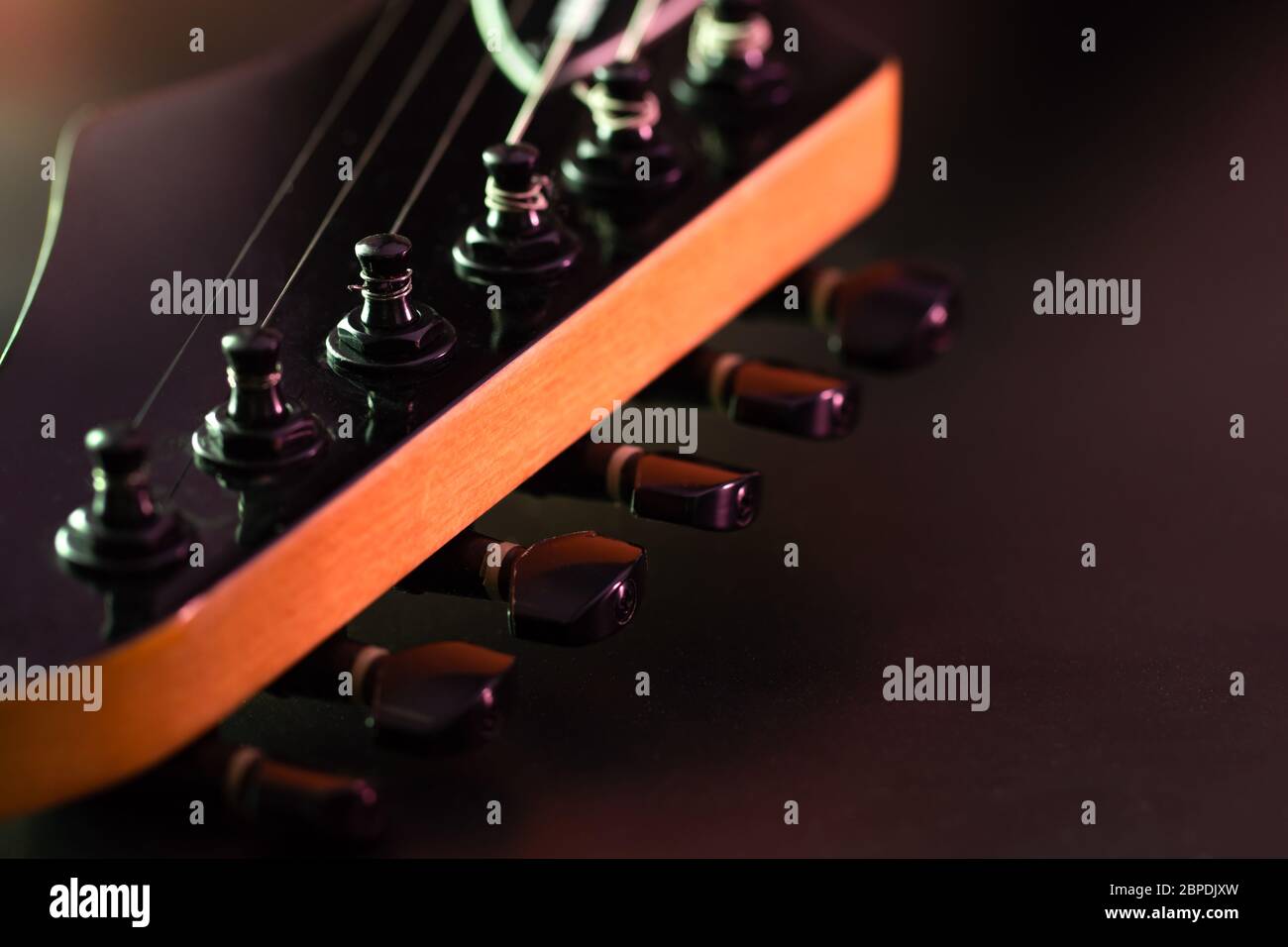 Closeup tuning key on the headstock of the black electric guitar in